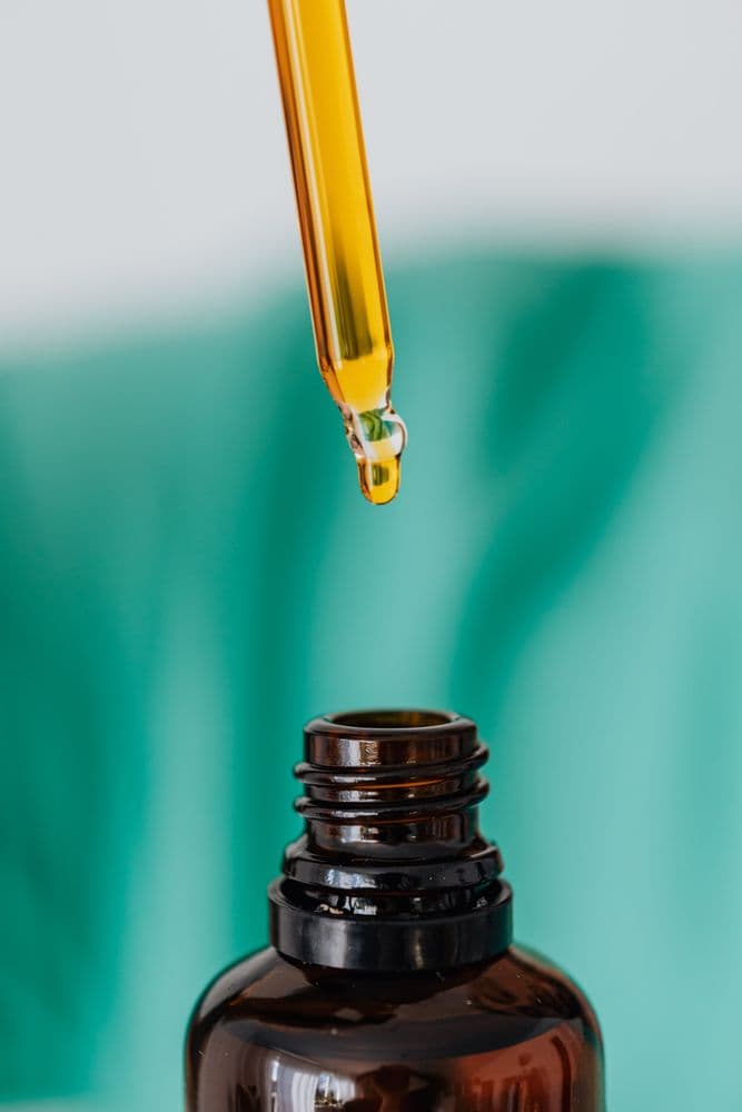 Pipette mit medizinischem Extrakt über einer Braunglasflasche